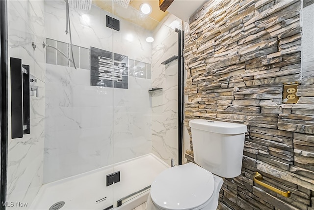 bathroom with tile walls, a shower with shower door, and toilet