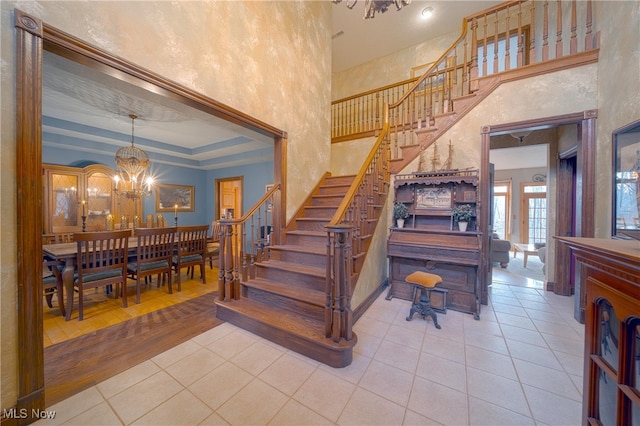 staircase featuring an inviting chandelier, a tray ceiling, hardwood / wood-style floors, and a towering ceiling