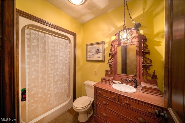 bathroom featuring a textured ceiling, vanity, toilet, and a shower with curtain