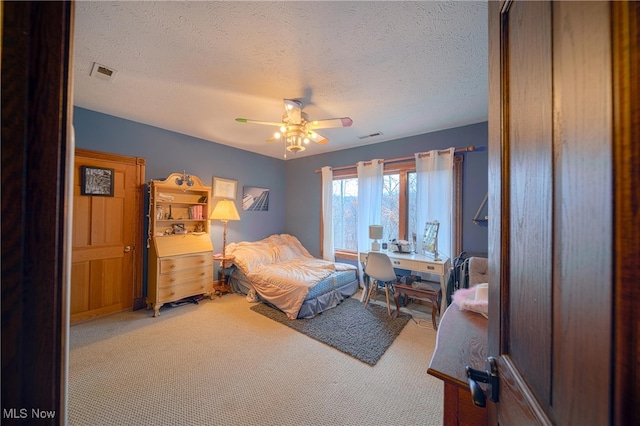 carpeted bedroom featuring a textured ceiling and ceiling fan