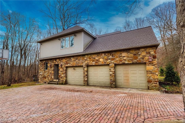 10000 Wisner Rd, Chardon, OH 44024 - view of side of property featuring stone siding, decorative driveway, and roof with shingles