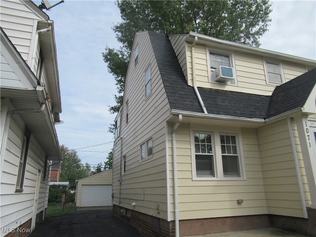 view of property exterior with cooling unit, a garage, and an outbuilding