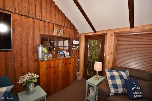 carpeted living room with vaulted ceiling with beams and wooden walls