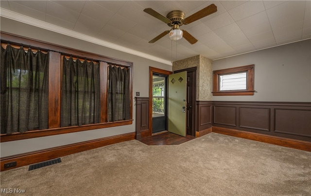 interior space with crown molding, dark carpet, and ceiling fan