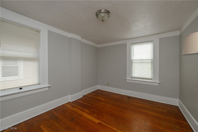 spare room featuring ornamental molding, a textured ceiling, and dark wood-type flooring