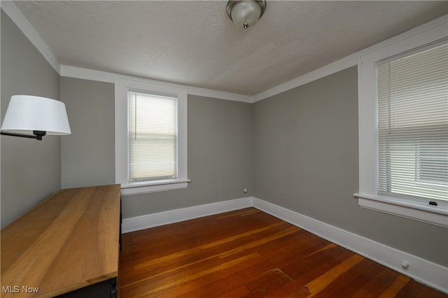 spare room featuring a textured ceiling and dark hardwood / wood-style flooring