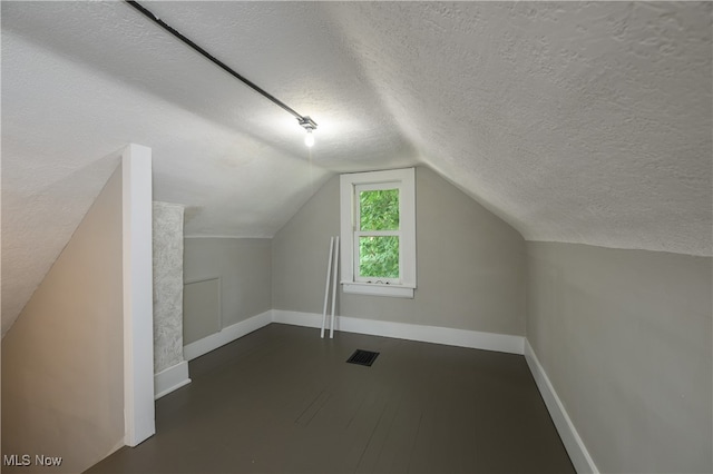 bonus room featuring vaulted ceiling and a textured ceiling