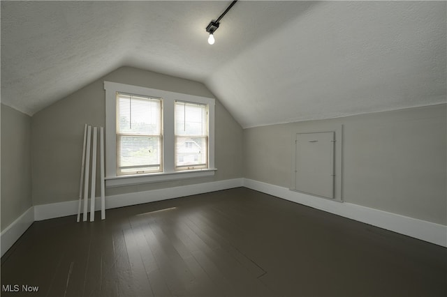 additional living space featuring a textured ceiling, dark hardwood / wood-style floors, and vaulted ceiling