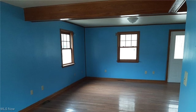 empty room with visible vents, wood finished floors, and baseboards