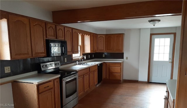 kitchen with black appliances, plenty of natural light, brown cabinets, and a sink