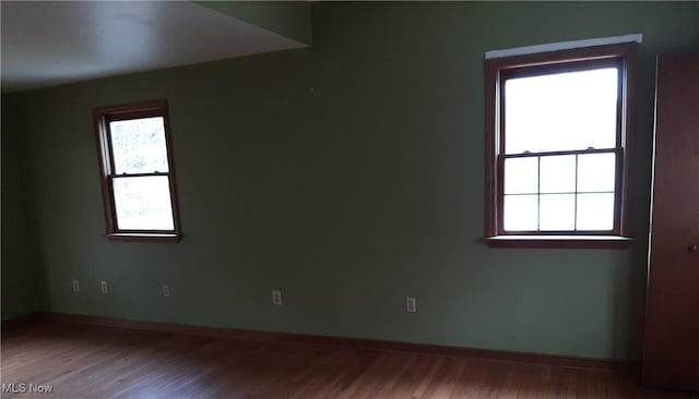 spare room with baseboards and wood finished floors