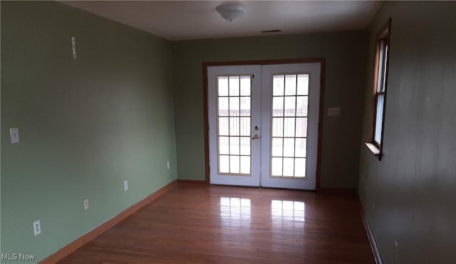 doorway with french doors, baseboards, visible vents, and wood finished floors