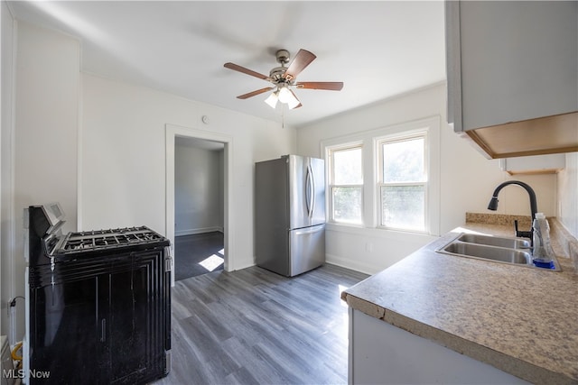 kitchen with stainless steel fridge, dark hardwood / wood-style flooring, black range with electric cooktop, ceiling fan, and sink