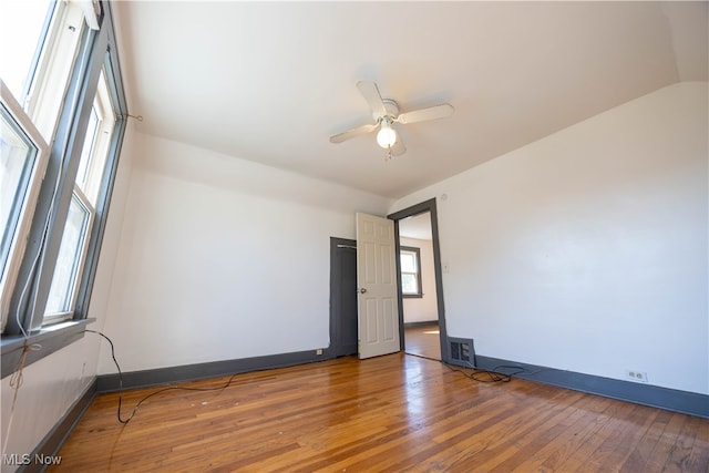 empty room with ceiling fan, dark hardwood / wood-style floors, and vaulted ceiling