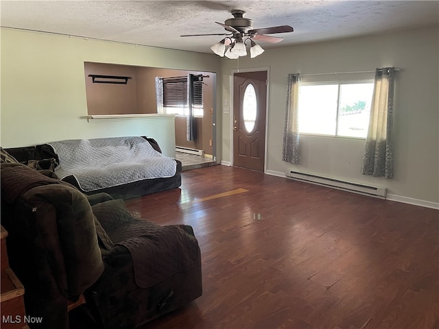 living room featuring ceiling fan, a textured ceiling, baseboard heating, and dark hardwood / wood-style floors