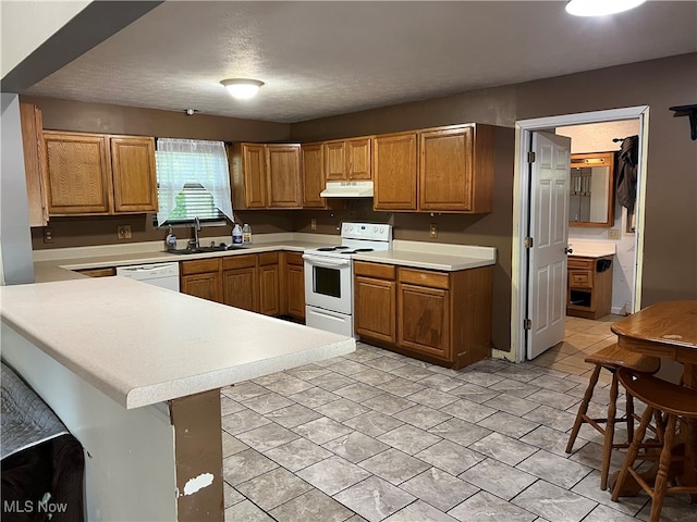 kitchen with a textured ceiling, electric range, sink, kitchen peninsula, and a kitchen breakfast bar