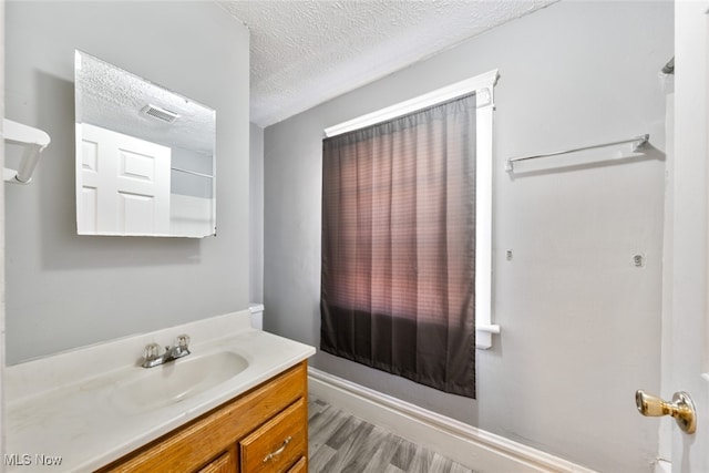 bathroom with wood-type flooring, vanity, and a textured ceiling