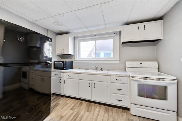 kitchen featuring white cabinets, sink, a paneled ceiling, light wood-type flooring, and white range with electric stovetop