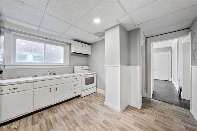 kitchen featuring white cabinets, light wood-type flooring, sink, and white stove