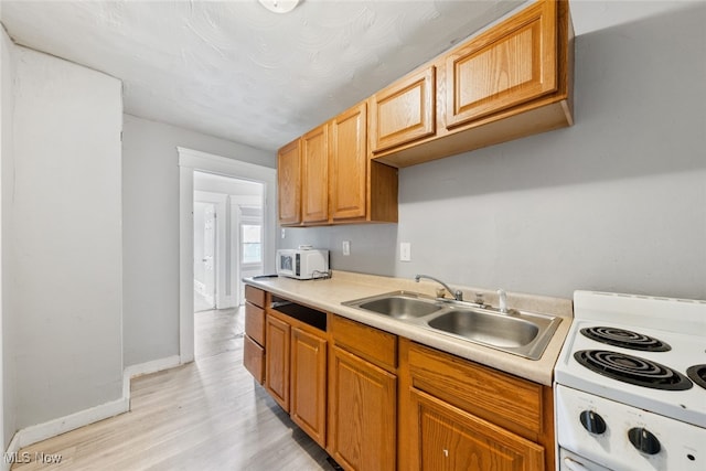 kitchen with light wood-type flooring, sink, and white appliances