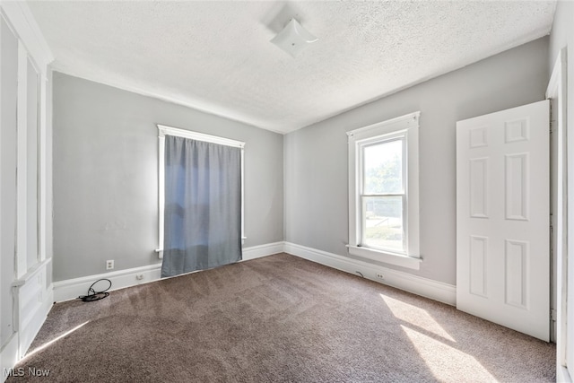 carpeted spare room with a textured ceiling