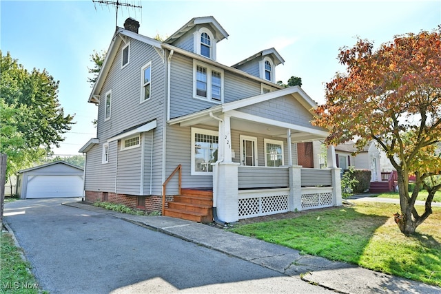 view of front of home featuring a front yard, a garage, an outdoor structure, and covered porch