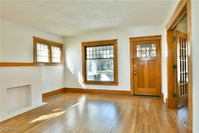 foyer with a textured ceiling, light wood-type flooring, and plenty of natural light