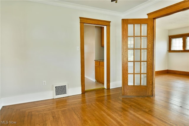 empty room featuring light wood-type flooring and crown molding