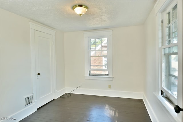 spare room with a textured ceiling and dark wood-type flooring