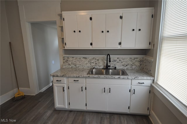 kitchen featuring light stone countertops, sink, backsplash, white cabinets, and dark wood-type flooring