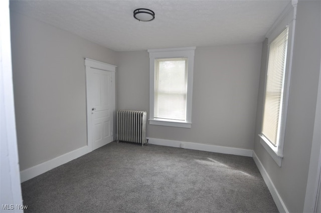 carpeted empty room featuring radiator