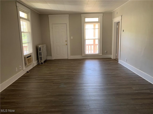 unfurnished room featuring baseboards, radiator, and dark wood finished floors