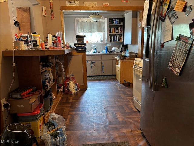 kitchen with stainless steel fridge, kitchen peninsula, white gas range oven, and dark parquet flooring