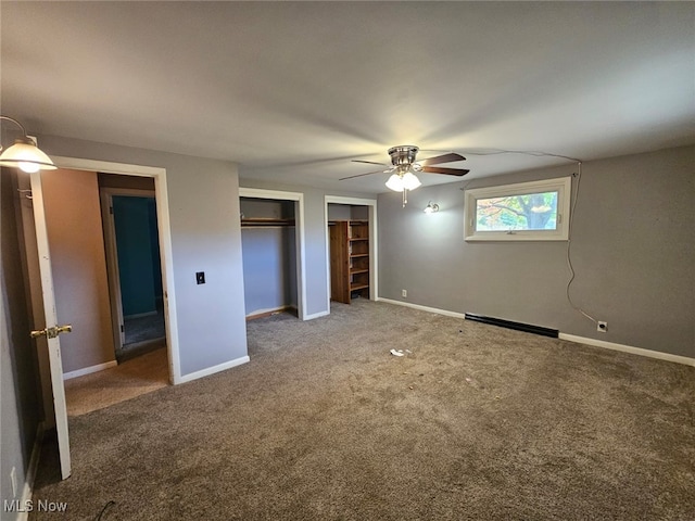 unfurnished bedroom featuring a baseboard radiator, two closets, ceiling fan, and carpet floors