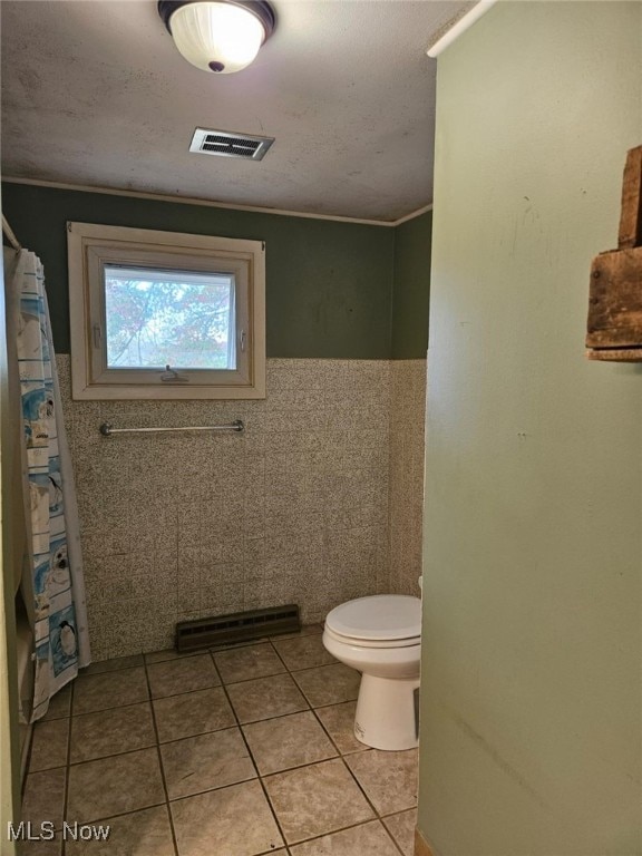 bathroom with tile walls, tile patterned flooring, toilet, and crown molding