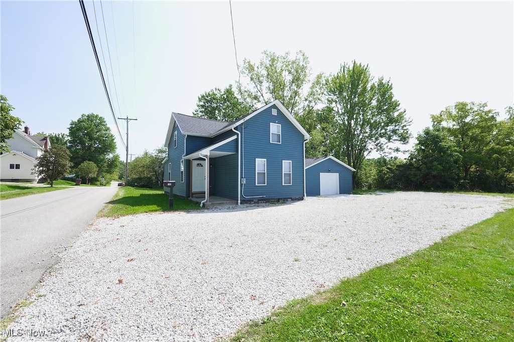 view of side of home with a garage, a lawn, and an outbuilding