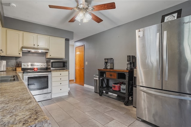 kitchen with stainless steel appliances, ceiling fan, light tile patterned floors, and cream cabinetry