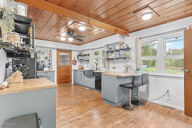 kitchen featuring kitchen peninsula, wooden ceiling, a breakfast bar, black dishwasher, and light wood-type flooring