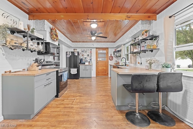 kitchen featuring wood ceiling, light wood-type flooring, kitchen peninsula, fridge, and stainless steel electric stove