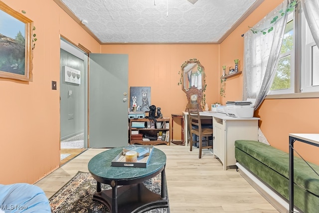 office area with a textured ceiling, built in desk, light hardwood / wood-style floors, and crown molding