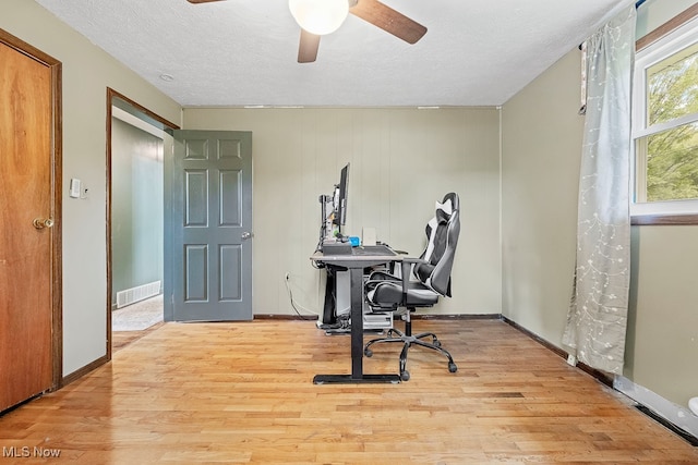 home office with ceiling fan, a textured ceiling, and light hardwood / wood-style flooring