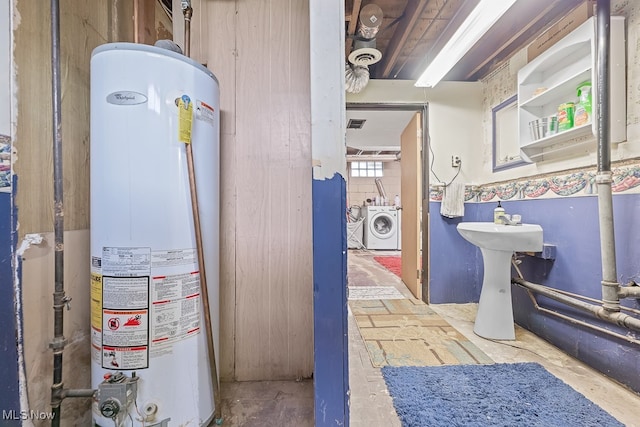 utility room with water heater, washing machine and dryer, and sink