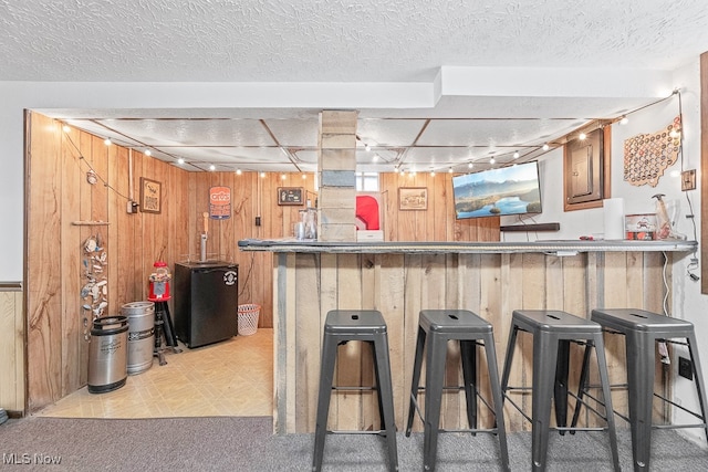 kitchen with rail lighting, wood walls, and a breakfast bar area