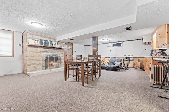 carpeted dining room with a textured ceiling and a stone fireplace