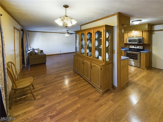 kitchen with ceiling fan with notable chandelier, appliances with stainless steel finishes, hardwood / wood-style flooring, and crown molding