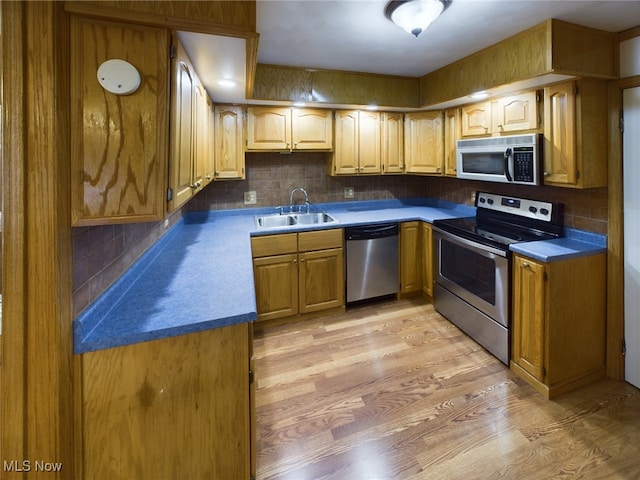 kitchen featuring appliances with stainless steel finishes, light wood-type flooring, sink, and tasteful backsplash