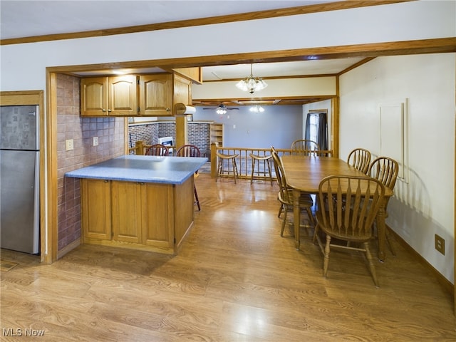 kitchen featuring light hardwood / wood-style floors, stainless steel refrigerator, an inviting chandelier, backsplash, and crown molding