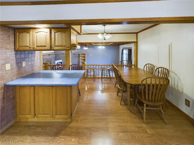 kitchen with hanging light fixtures, tasteful backsplash, crown molding, an inviting chandelier, and hardwood / wood-style flooring