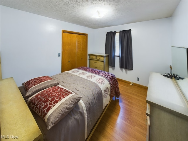 bedroom featuring wood-type flooring, a textured ceiling, and a closet