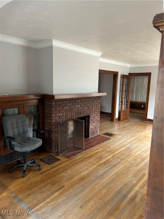 unfurnished living room with ornamental molding, hardwood / wood-style floors, and a brick fireplace